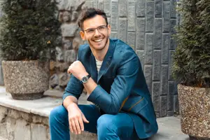 Man in blue suit and glasses sitting outside