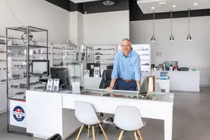 A man stands behind a desk in a shop with a sign reading Vuarnet France