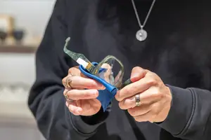 An adult person holding a pair of glasses with a blue cloth in their hands