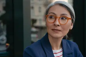 Woman wearing glasses and a blue blazer with a striped shirt underneath