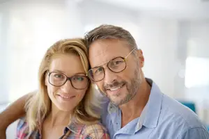 A smiling man and woman posing for a photo while wearing glasses
