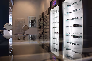 A room with glass display cases and mirrors, showcasing sunglasses and eyeglasses on shelves.