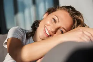Closeup of a smiling woman laying on a couch in a living room