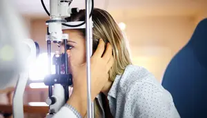 A woman examining her eyes with a machine inside an eye clinic