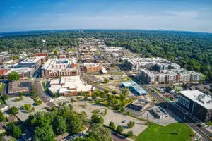 An aerial view of a city with many buildings, trees, and a parking lot