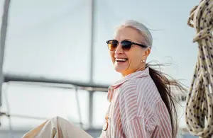 Elderly woman in sunglasses smiling and looking ahead on a boat