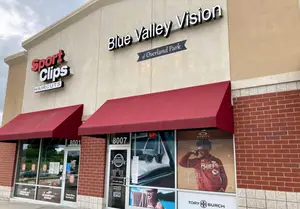 Blue Valley Vision, a sports store, has a red awning, a brick wall, and a sign with a man in a red NFL jersey.