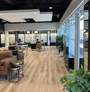 Interior view of an Overland Park optometrist's office with wooden floors, large windows, and several people sitting at tables and working on computers.