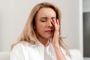 A Overland Park woman is looking down while covering her eyes with her hand, probably she is feeling headache