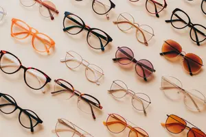 A collection of glasses of different colors and styles placed on a light brown background.