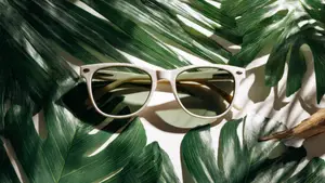 A pair of white sunglasses with a green leaf background