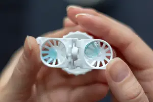 Close-up of a person's hand holding a pair of contact lenses, possibly for an advertisement.