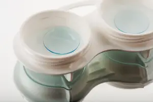 Two clear contact lenses in a plastic case on a white background