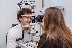 a man getting his eye examined by a female doctor