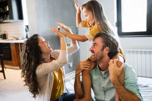 A family with a young girl is playing on the floor in their living room.