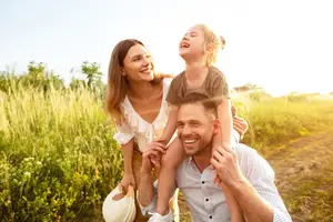 A smiling man and woman with a young girl standing in a field
