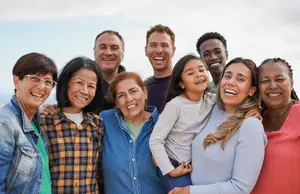 A group of people, including a child, are smiling and posing for a photo in an outdoor setting.
