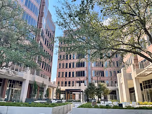 A commercial building with trees and chairs in front of it.