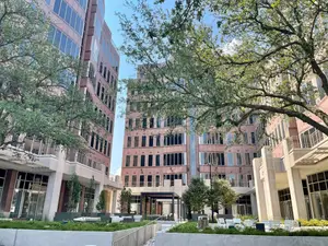 A commercial building with trees and chairs in front of it.