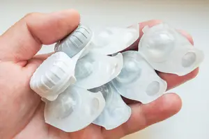 A person's hand holding several transparent eyeglass lenses