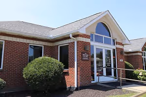 A brick building with a gray roof and glass windows, displaying a sign reading 'St. Westtown Eye Care', located on a sunny day.
