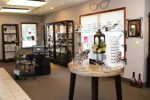 Inside a small business office with a desk, chair, table, and shelf with eyeglasses on display
