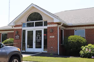 A gray car is parked in front of the building with the text 'MODIGATION EYE CARE' and number '315' on the wall.