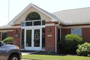 A gray car is parked in front of the building with the text 'MODIGATION EYE CARE' and number '315' on the wall.
