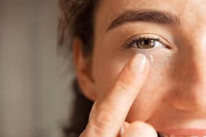 Closeup of a woman's face as she puts in a contact lens