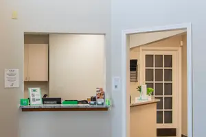 A well-lit reception area with a desk, cabinets, and a door leading to another room.
