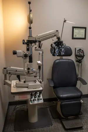 An ophthalmic diagnostic device is beside a reclining chair in a room.