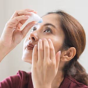 middle aged woman applying glaucoma eye drops