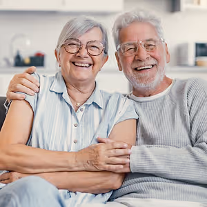 happy senior couple on sofa at home