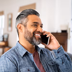 happy mid indian man talking on phone
