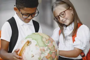 A boy and a girl are looking at a globe with smiling faces