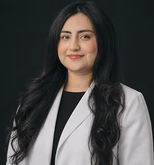 Dr. Mariam's portrait with a black background and white coat, smiling for the camera
