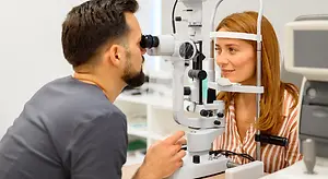 Optometrist examining a woman's eyes with a slit lamp