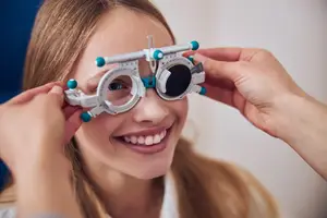 A young girl wearing a pair of phoropter glasses used to check her eye sight at an optometrists office