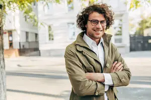 A man standing on the side of the road with his arms crossed, smiling and looking at the camera.