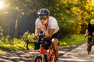 Two men riding bicycles on a dirt path surrounded by trees