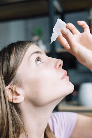 Closeup of a woman with her eyes closed while applying eye drops