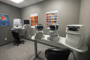 An optometrist's room with two Nikon eye examination machines and a chart on the wall