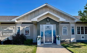 Front view of the Eye Care building with a sign that reads Eye Care, two vases with flowers, and a pathway leading to the entrance.
