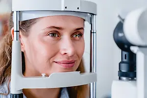 A woman looks into an eye examination machine.