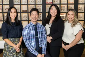 Four individuals posing for a photo in an optical shop