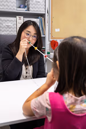 A woman is playing with a child using a string of beads