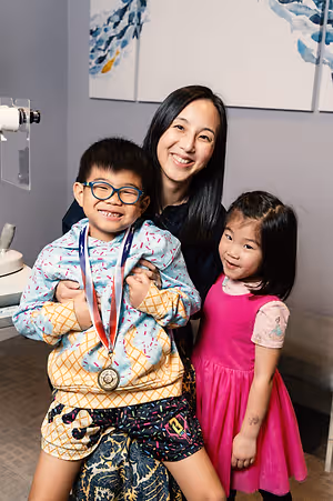 A woman and two kids are posing for a photo inside a room, maybe in a studio