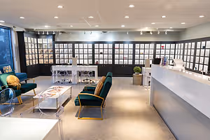 The interior of a modern office or reception area with glass cabinets, desks, and chairs arranged in a room.