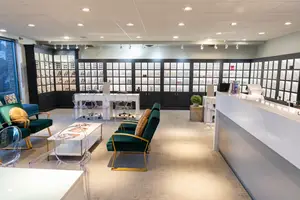 The interior of a modern office or reception area with glass cabinets, desks, and chairs arranged in a room.