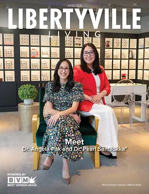 A photo of two women, Dr. Angela Pak and Dr. Pearl Santilukka, sitting on a chair in a room with a table, a potted plant, and a wall displaying eyeglasses. The photo has a watermark that reads 'Libertyville Living' and 'Meet Dr. Angela Pak and Dr. Pearl Santilukka'.